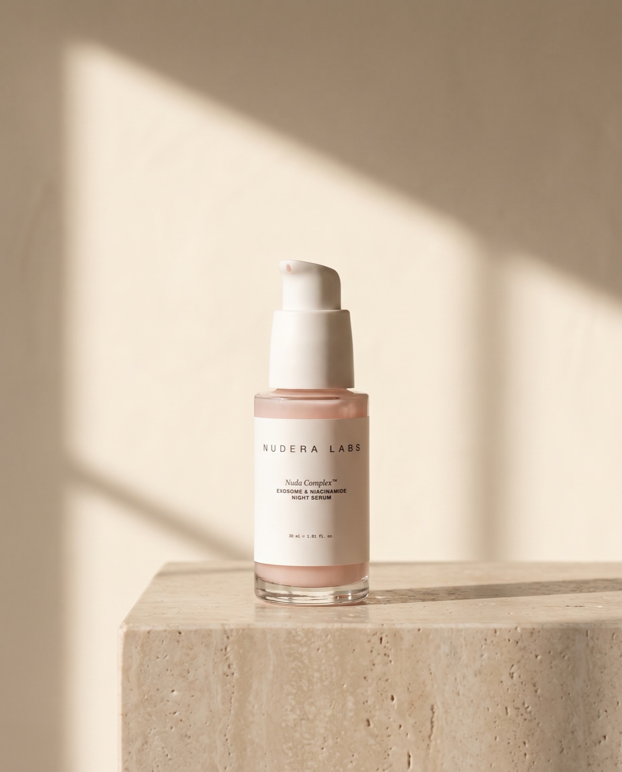 NUDA COMPLEX night serum on a travertine plinth in window light